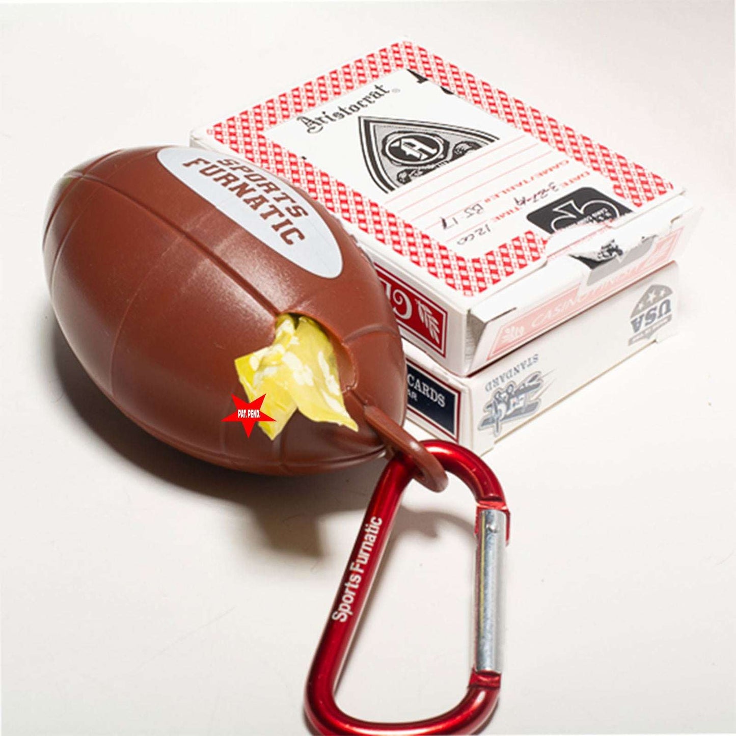 Sports Furnatic's poop bag dispenser named The Tail Gater®. It is laying next to two decks of cards stack on top of each other, to show how small the unit is. This unit is customized with a Red carabiner and a Yellow bag roll.